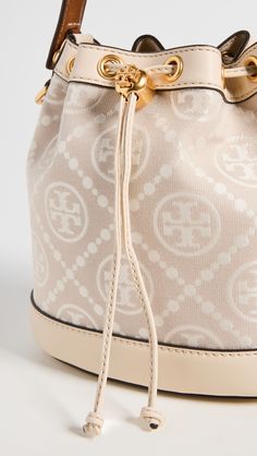 Find TORY BURCH T Monogram Bucket Bag on Editorialist. Fabric: Jacquard. Structured silhouette. Gold-tone hardware. Monogram pattern. Leather trim. Drawstring top. Patch interior pocket. Optional, adjustable strap. Suede lining. Weight: 23oz / 0.65kg. Imported, Cambodia. Measurements: Height: 8.25in / 21cm Length: 8.25in / 21cm Depth: 4.75in / 12cm Strap drop: 21.75in / 55cm Handle drop: 4in / 10cm Tory Burch Bucket Bag, T Monogram, Neutral Bag, Drop Logo, Mini Bucket Bags, Drawstring Top, Monogram Pattern, Monogram Bag, Tory Burch Bag