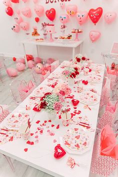 a table set up for a valentine's day party with pink and red decorations