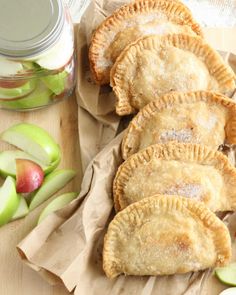 four pies sitting on top of a wooden cutting board next to an apple jar