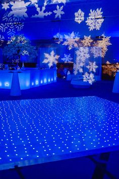 the dance floor is lit up with blue lights and snowflakes on it