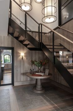 a room with some lights on the ceiling and a table in front of it near stairs