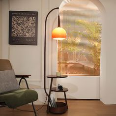 a living room with a chair, table and lamp on it's side stand