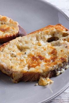 two pieces of bread sitting on top of a plate with cheese and meat in it