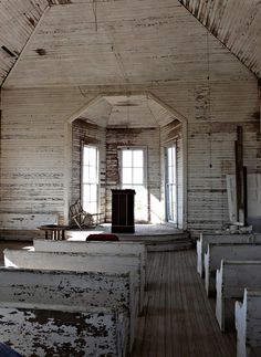 an old church with wooden pews in the foreground and windows on the far wall