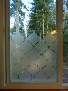 a window that has some glass on the side of it and trees in the background