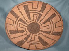 a brown and white woven basket on a blue cloth with an intricate design in the center