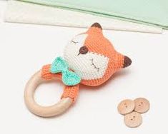 a knitted fox ring rattler next to two wooden buttons on a white surface