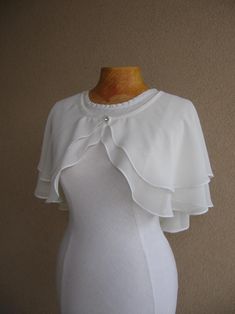 a woman's white dress with ruffles on the shoulders and collarline