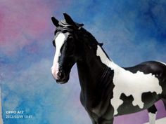 a black and white toy horse standing on top of a wooden table next to a wall