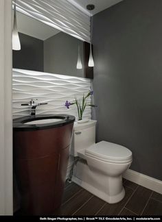 a white toilet sitting next to a sink in a bathroom under a mirror and lights