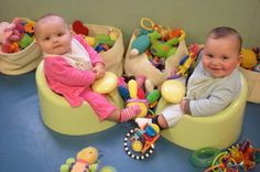 two babies are sitting in their toys on the floor