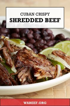 an image of shredded beef with beans and limes in a white bowl on a table