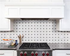 a stove top oven sitting inside of a kitchen next to white cabinets and counter tops