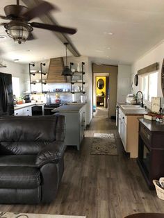 a living room filled with furniture and a ceiling fan in the middle of a kitchen