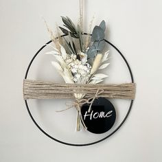 a wreath with flowers tied to it hanging on the wall next to a sign that says home