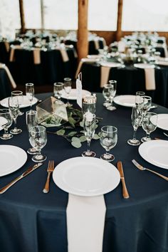 the table is set with white plates, silverware and place settings for an elegant dinner