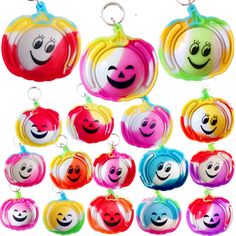 many different colored pumpkins with faces painted on them, all hanging from key chains