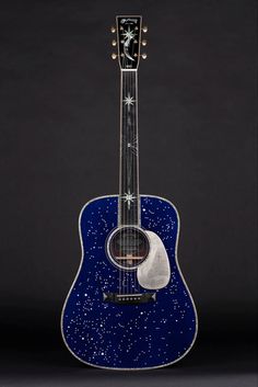 a blue acoustic guitar with stars on the top and bottom, against a black background