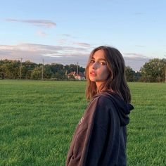 a woman standing in the middle of a field with her head tilted to the side