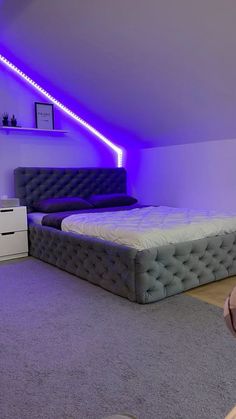 a bed room with a neatly made bed and purple lighting