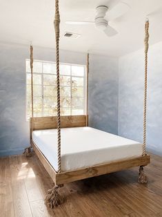 a bedroom with blue walls and wood flooring has a white bed in the middle