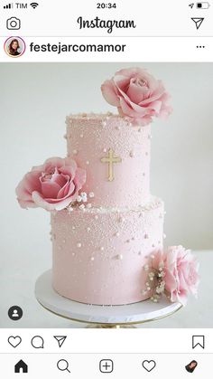 a three tiered cake with pink flowers on top and a cross on the side