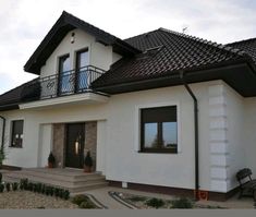 a white house with black roof and balcony