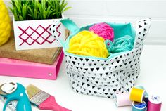 a basket filled with yarn and scissors next to some other crafting supplies on a table