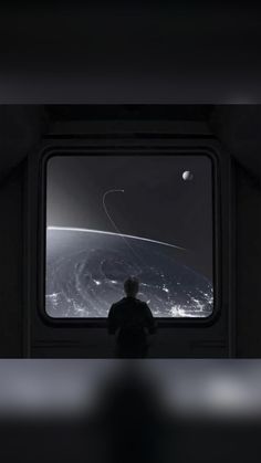 a man looking out the window at an image of saturn and its moon taken from space