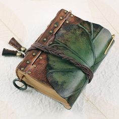 an old book is adorned with leather and brass hardwares as it sits on a white surface