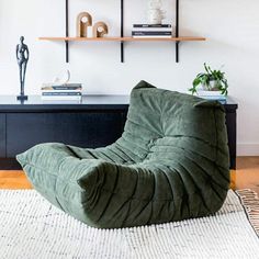 a green bean bag chair sitting on top of a rug next to a black table