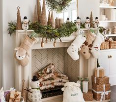 a fireplace decorated for christmas with stockings and snowmen