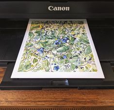 an image of a printer that is on top of a wooden table with the word canon printed on it