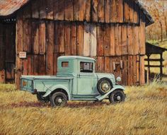 an old blue truck parked in front of a barn with a wooden building behind it