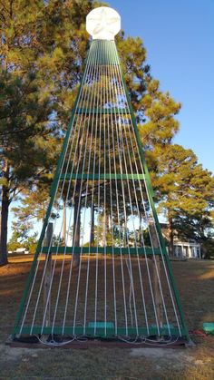 a large metal structure in the middle of a field with trees and grass around it