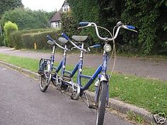 three bikes are parked on the side of the road in front of some bushes and trees