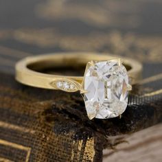 an old - fashioned diamond ring sits on top of a book with gold trimmings