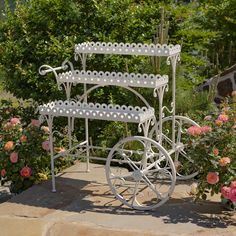 a three tiered white metal carriage with roses in the background