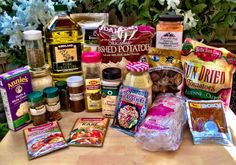 an assortment of food and condiments on a picnic table with flowers in the background