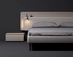 a bedroom with a bed, night stand and lamp on the wall next to it