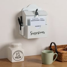 a coffee cup and pen holder on a wooden desk next to a mug, scissors, and sugar jar