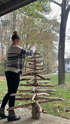 a woman standing next to a wooden christmas tree