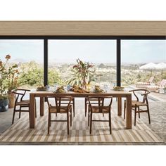 a dining room table with chairs and an umbrella in front of a large window overlooking the city