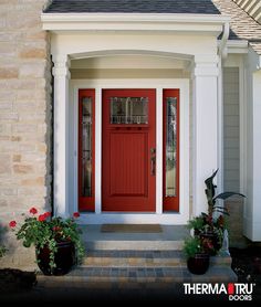 a red front door with two planters on either side and a brick walkway leading up to it