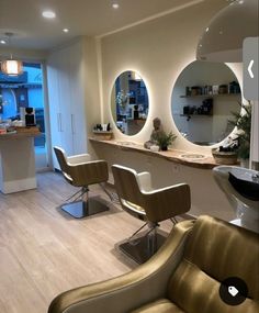 a hair salon with chairs, mirrors and lights on the wall in front of it