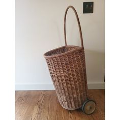 a brown wicker basket sitting on top of a wooden floor next to a wall