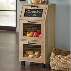 a wooden cabinet with two drawers filled with fruits and vegetables next to a wicker basket