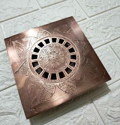 a square shaped metal object sitting on top of a white tile floor