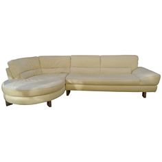 a white leather sectional sofa with chaise lounge and footstool on an isolated white background