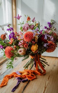 a bouquet of flowers sitting on top of a wooden table next to a window sill